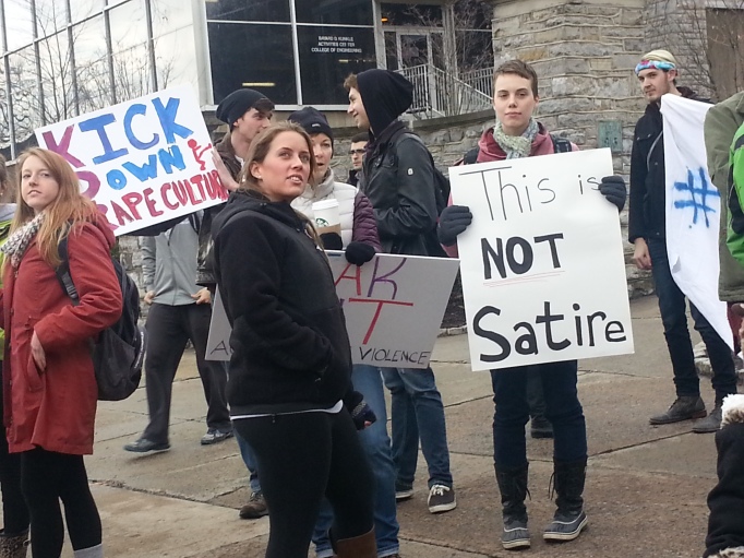 Signs at that protest rally that say "Kick down rape culture" and "This is not satire."
