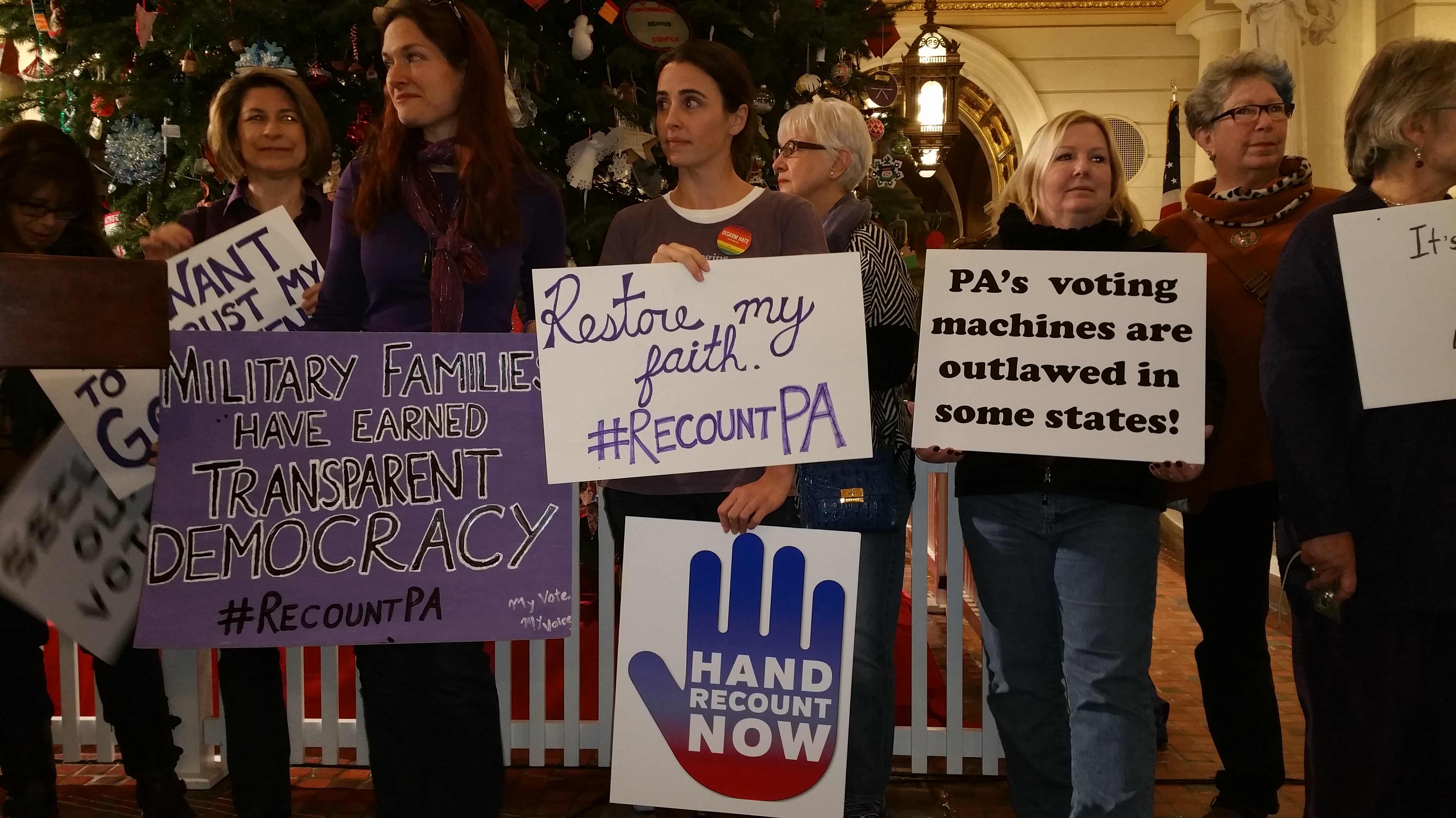 Picture of people holding signs about why they want a recount of the Presidential and US Senate races in the 2016 elections in Pennsylvania