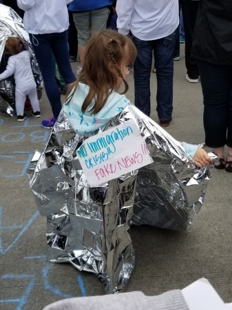 picture of a child wearing aluminum foil with a sign saying that the statement "Fake News! No Immigration Crisis!"